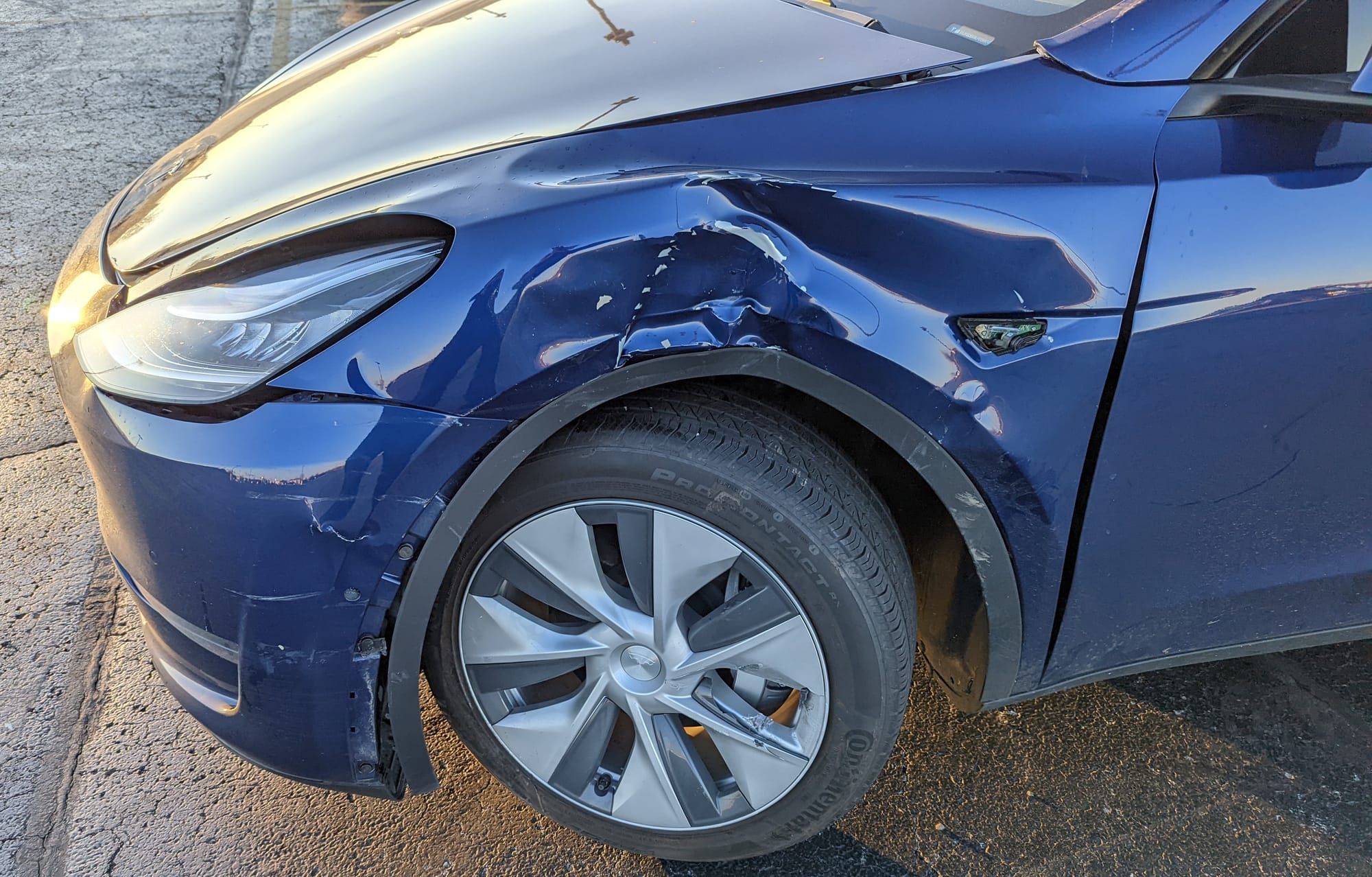 Damaged front left wing of a blue sedan